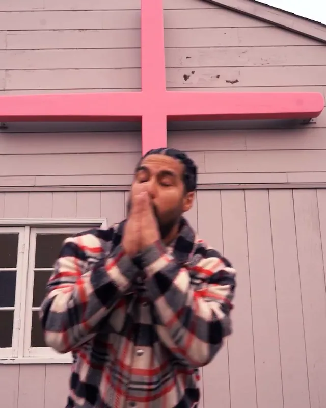Al Bear with his hands together under the pink cross